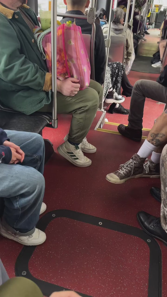 model holding a pink mesh market bag on a bus