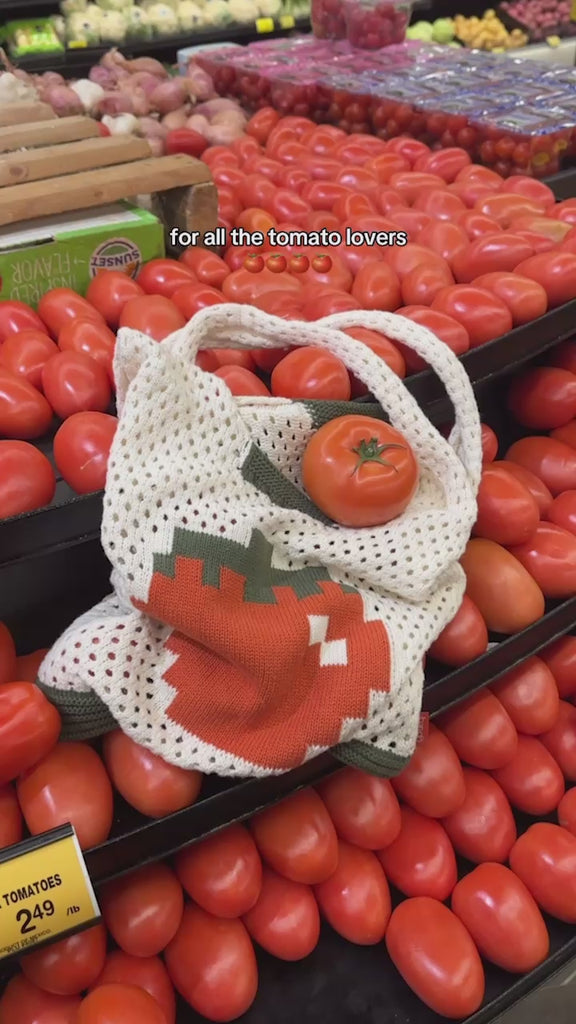 model putting tomatoes in cream open knit market bag with red tomato in the middle and green trim