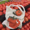 model putting tomatoes in cream open knit market bag with red tomato in the middle and green trim
