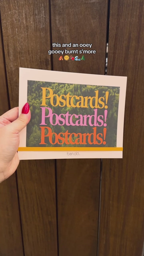 model showcasing postcards in colorful postcards book with yellow elastic closure strap