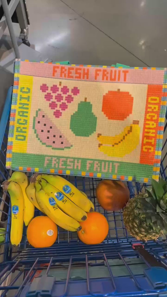 model grocery shopping with rattan market tote with colorful fruit tile accents