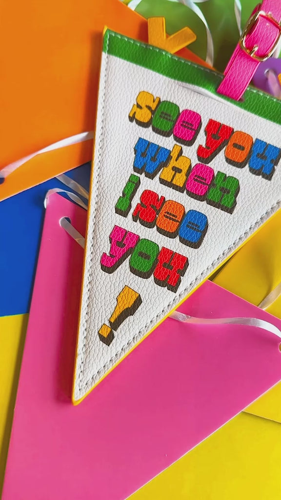 model showcasing cream pennant luggage tag with colorful 'see you when i see you!' front and pink, yellow and green trim
