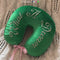 model showcasing green travel pillow with white embroidered 'what a dream' text and pink ribbon