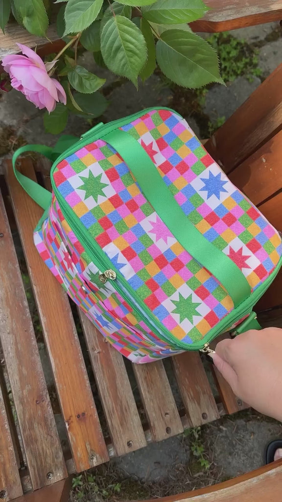 model pulling colorful cups out of colorful 'quilted' star lunch bag with green trim and strap and front pocket