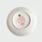 bottom of cream ring tray with pixelated floral and bow print that says 'have a nice day' in the center