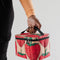 model holding baggu puffy lunch bag with pink ground and all over strawberry print